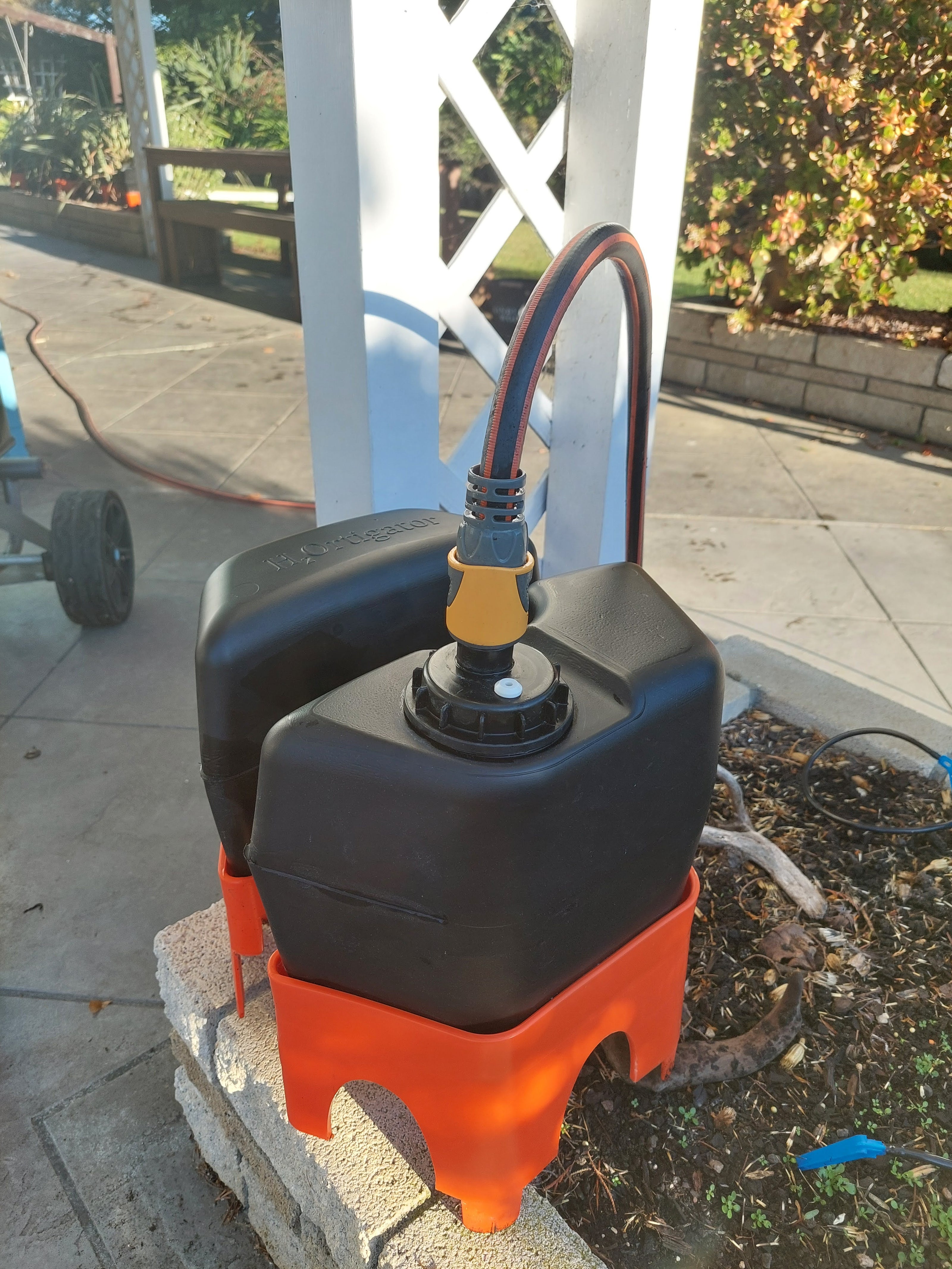 a h2ortigator unit on the edge of a garden with a yellow hose fitting connected to the water supply